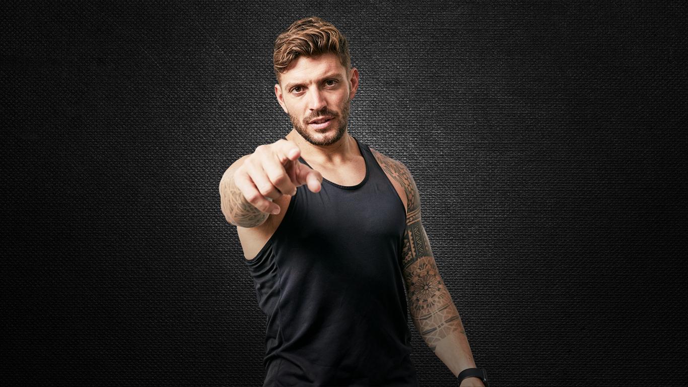 Man with tattoos pointing towards the camera